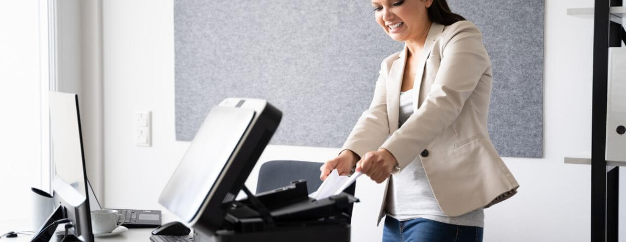 Frustrated woman pulling paper jam out of printer