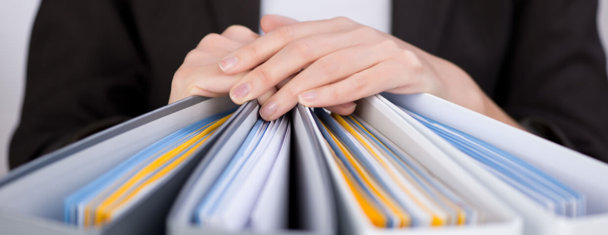 A woman holding her hands on a stack of binders full of papers.