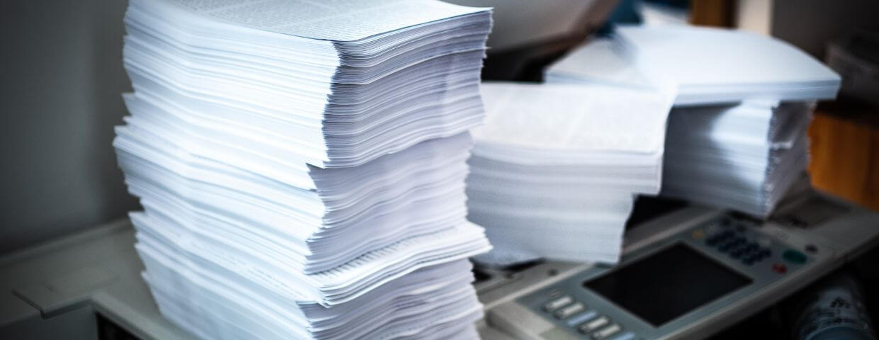 stacks of printer paper on and around copier